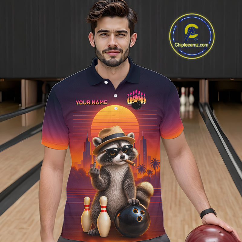 A man wearing a custom bowling-themed polo shirt with a raccoon graphic, standing in a bowling alley. The shirt features a sunset gradient background with a raccoon wearing a hat and holding bowling pins and a ball.