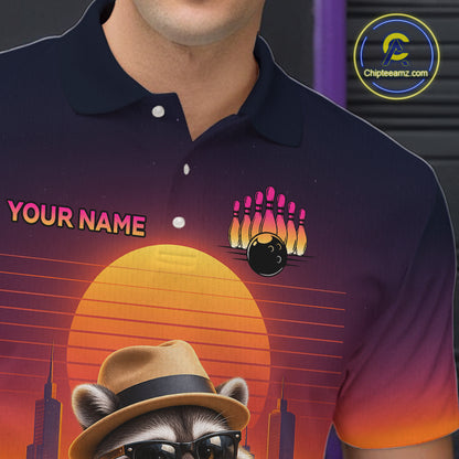 A close-up of a person wearing a dark navy polo shirt with a colorful retro-style graphic print. The design features a large orange sunset, a raccoon in a hat and sunglasses, bowling pins, a bowling ball, and the text 'YOUR NAME' with a bowling pin and ball motif.