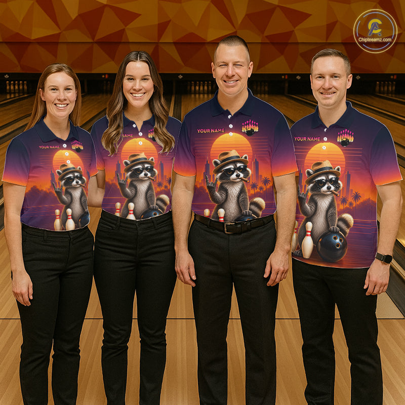 Four people standing in a bowling alley wearing matching custom-printed short-sleeve polo shirts with a raccoon and bowling graphic, paired with black pants. The shirts feature a sunset gradient background with the text 'YOUR NAME'.