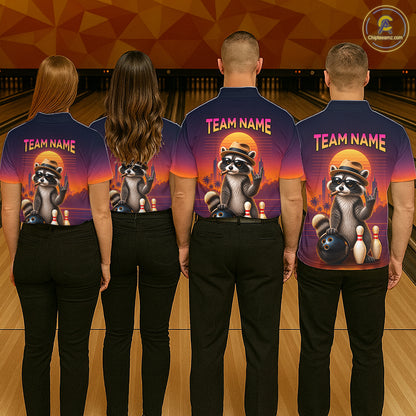 Four people standing with their backs to the camera in a bowling alley, wearing matching dark blue short-sleeve shirts with a large raccoon graphic and the text 'TEAM NAME' on the back. The shirts have a purple-to-orange gradient design with bowling-themed artwork.