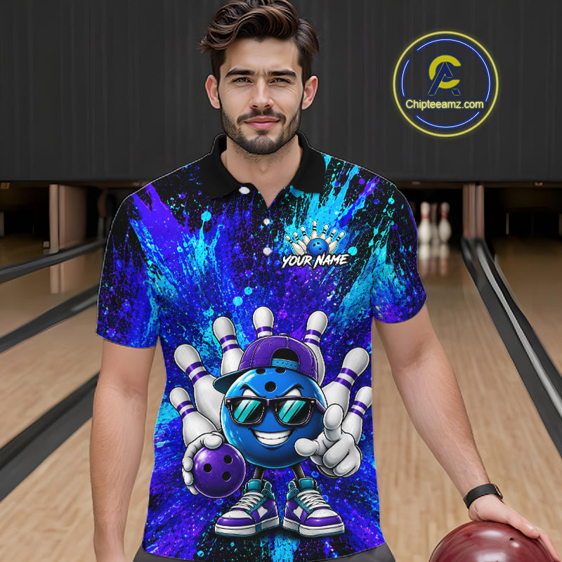 A man wearing a custom bowling-themed short-sleeve polo shirt with a blue and purple cosmic paint splatter design and a cartoon bowling ball graphic, standing in a bowling alley holding a bowling ball.