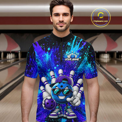 A man wearing a short-sleeve bowling-themed graphic t-shirt with a blue and purple paint splatter design and a cartoon bowling ball character. The background shows a blurred bowling alley.
