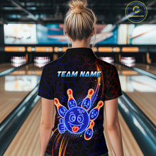 Load image into Gallery viewer, Woman standing in a bowling alley wearing a black neon-style bowling polo shirt with a glowing blue cartoon bowling ball mascot, fiery orange pin graphics, and custom name text.