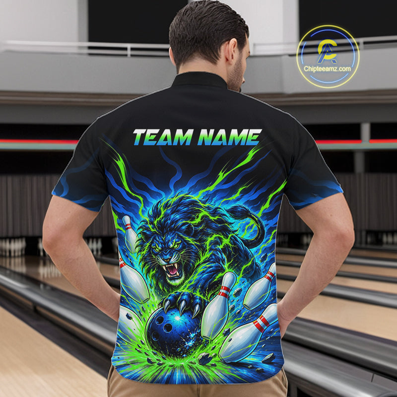 A man viewed from behind wearing a black short-sleeve bowling shirt with a large back graphic of a roaring blue lion crushing bowling pins and a bowling ball, with the text 'TEAM NAME' across the upper back. The background shows bowling lanes in a bowling alley.
