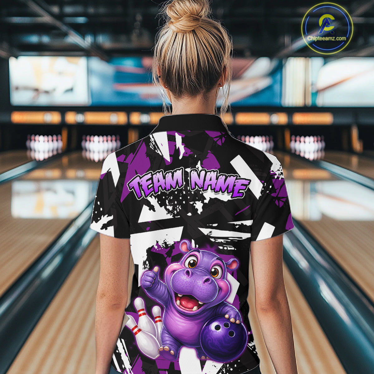 Woman wearing of a black, white, and purple bowling quarter zip shirt featuring a cheerful purple hippo holding a bowling ball, with custom player name text.