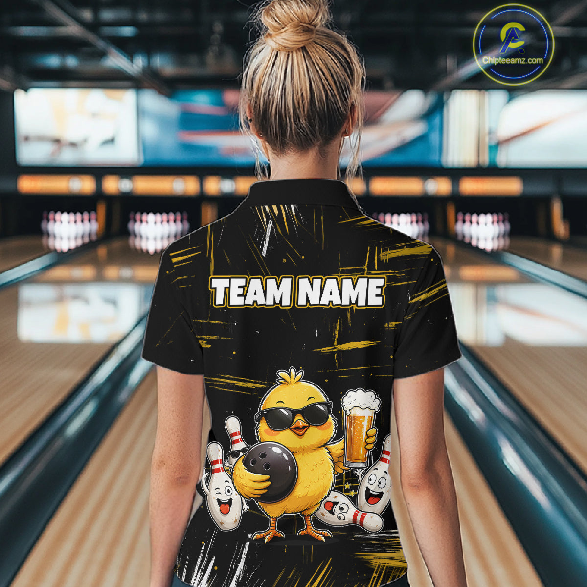 Women wearing bowling quarter zip shirt featuring a chick holding a bowling ball surrounded by smiling pins and beer graphics on black yellow background.