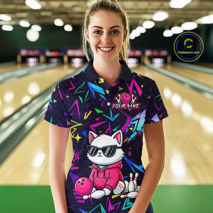 Woman wearing a black bowling polo with neon geometric patterns, custom team text, and a white cat mascot in sunglasses holding a pink bowling ball.