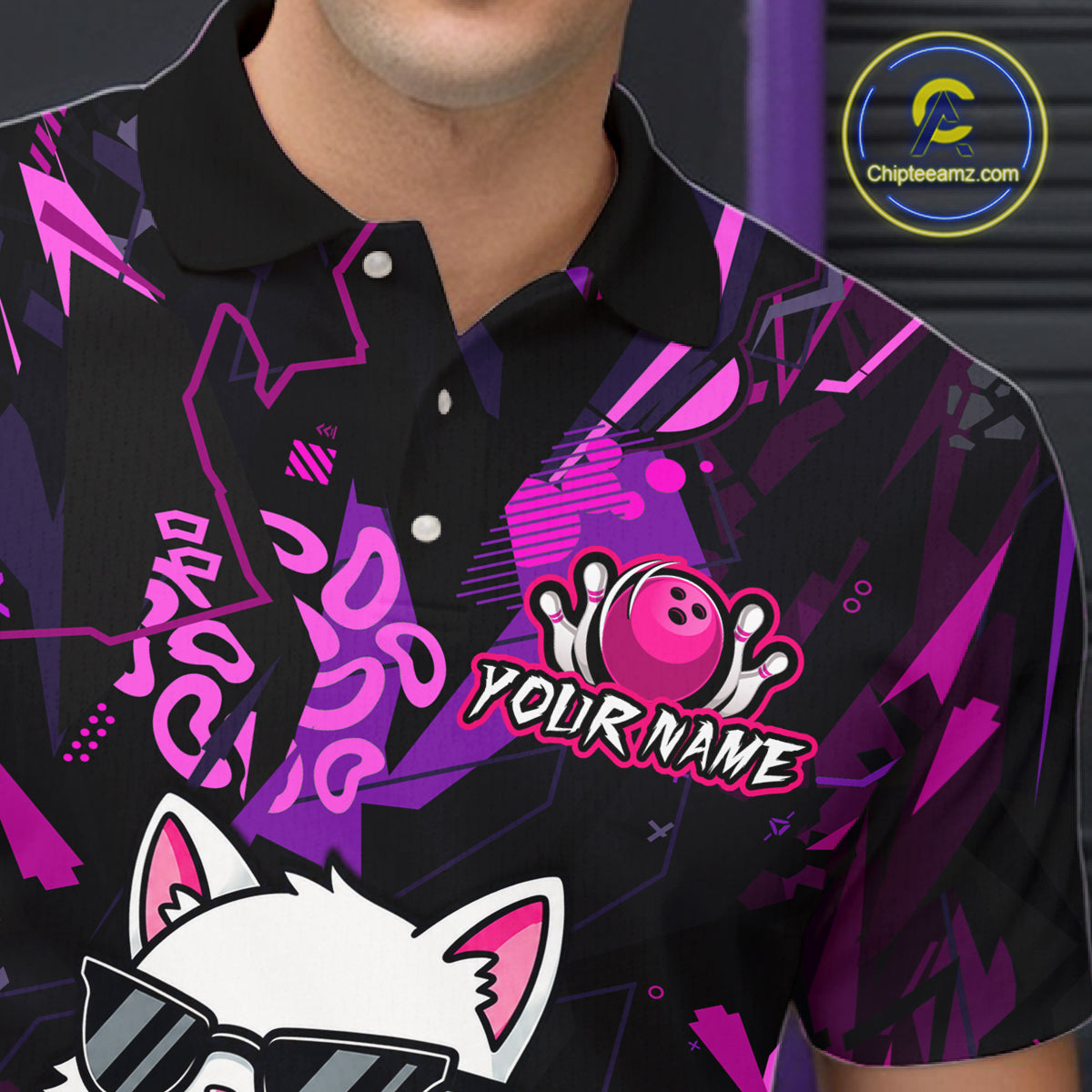 A close-up of a person wearing a black short-sleeve polo shirt with a vibrant purple and pink abstract graphic pattern. The shirt features a customizable bowling-themed graphic with a bowling ball, pins, and the text 'YOUR NAME'.