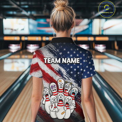 A woman viewed from behind wearing a short-sleeve bowling-themed polo shirt with a patriotic red, white, and blue design, cartoon bowling pins, and the text 'TEAM NAME' on the back. The background shows a blurred bowling alley interior.