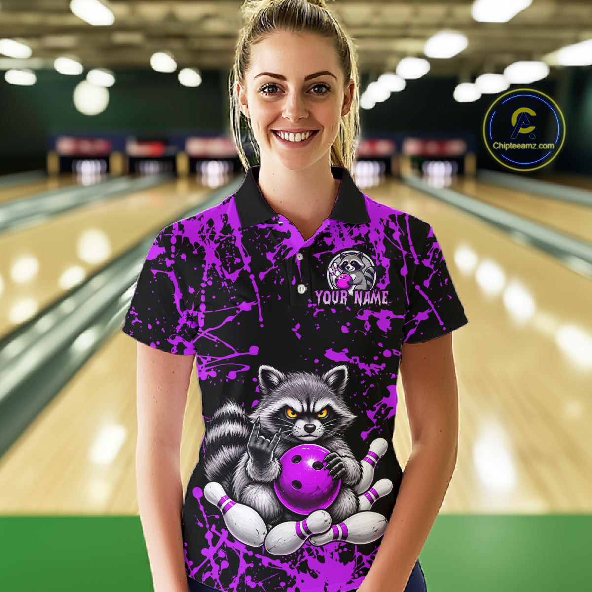 A woman wearing a custom bowling-themed polo shirt with a raccoon holding a purple bowling ball, set against a blurred bowling alley background. The shirt features a black base with vibrant purple paint splatters and a detailed raccoon graphic.
