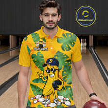 Load image into Gallery viewer, Man in a bowling alley wearing a bright yellow tropical polo shirt with green leaf patterns, custom name text, and a smiling banana mascot holding a bowling ball.