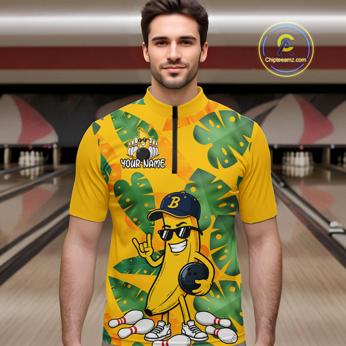 Man in a bowling alley wearing a bright yellow tropical quarter zip shirt with green leaf patterns, custom name text, and a smiling banana mascot holding a bowling ball.