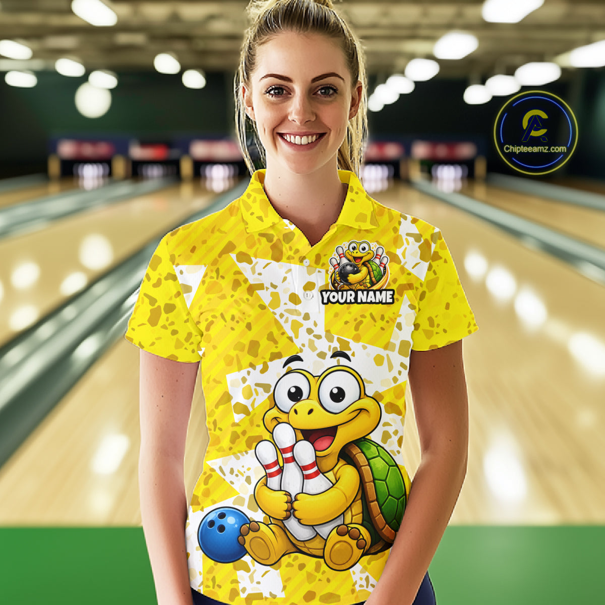 Woman wearing a yellow bowling shirt with cartoon turtle design in a bowling alley.