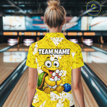Load image into Gallery viewer, Woman wearing a yellow bowling-themed shirt with a cartoon turtle holding a bowling ball in a bowling alley.