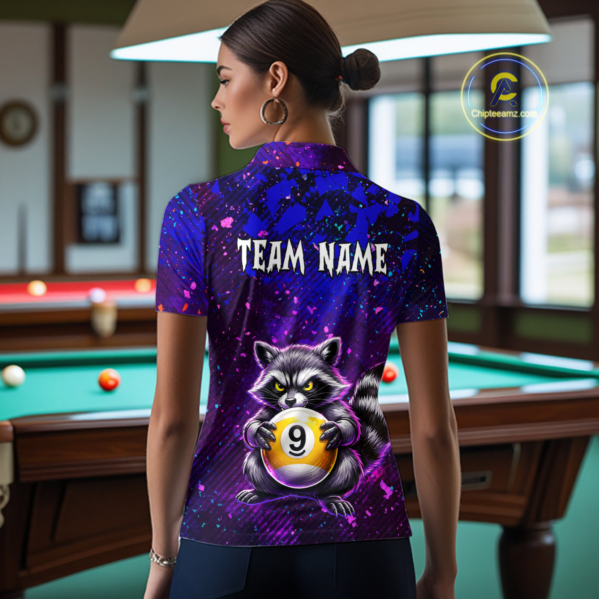 Woman wearing a purple shirt with a raccoon design and 'Team Name' text in a pool hall.