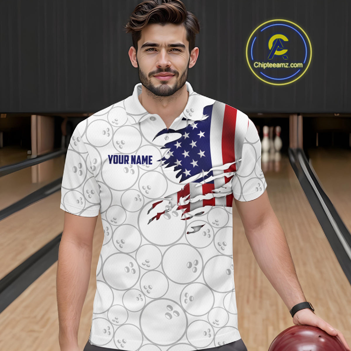 A man wearing a white bowling-themed polo shirt with a distressed American flag graphic and bowling ball pattern, standing in a bowling alley. The shirt features 'YOUR NAME' on the chest.