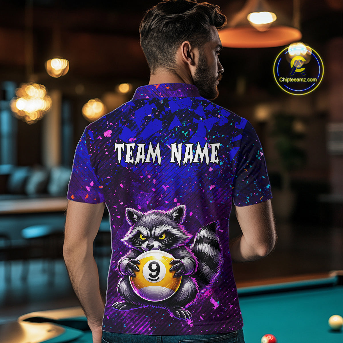 Person wearing a colorful polo shirt with a raccoon and pool ball design, standing in a bar.