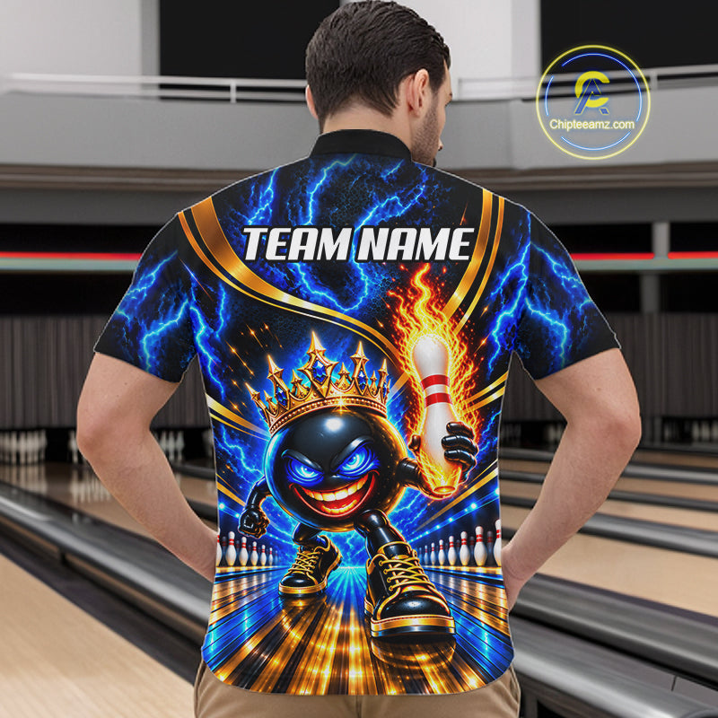 A man wearing a short-sleeve bowling-themed graphic polo shirt with a black, blue, and gold design featuring a cartoon bowling ball character, lightning effects, and a crown. The background shows blurred bowling alley lanes.