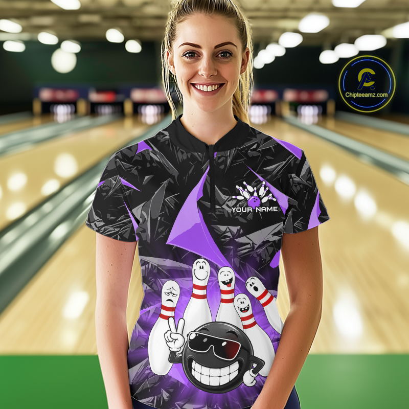 A woman stands in a bowling alley wearing a black and purple bowling-themed short-sleeve polo shirt with a cartoon bowling ball and pins graphic. The background shows blurred bowling lanes, and a circular 'Chilewich.