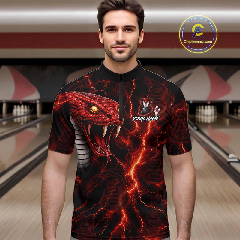 A man wearing a black short-sleeve bowling shirt with a fiery red and orange snake graphic and lightning print, standing in a bowling alley. The shirt features a half-zip collar and a customizable name graphic on the chest.