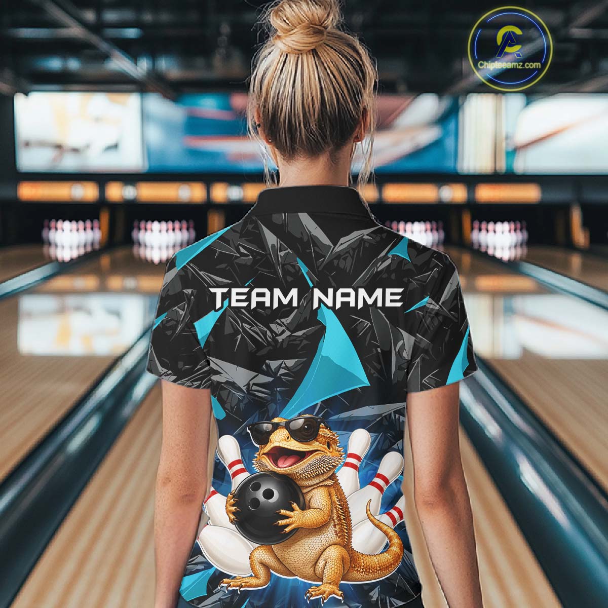Women’s turquoise bearded dragon bowling quarter zip shirt, back view on female model in bowling lane 