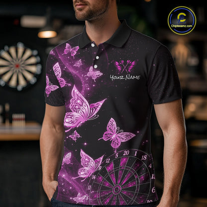 A man wearing a black short-sleeve polo shirt with a vibrant purple and pink butterfly and dartboard graphic print, set against a blurred bar background.