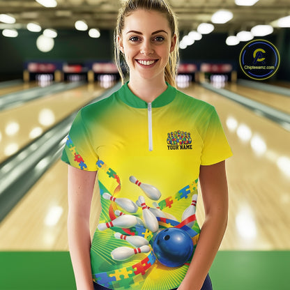 Female model in a bowling lane wearing a green and yellow quarter-zip shirt, autism puzzle bowling ball and pins with vibrant graphic style.