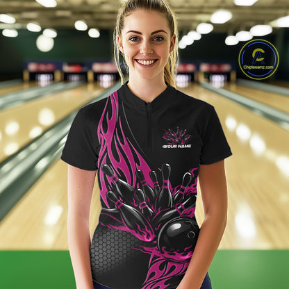 Female model front view in bowling alley wearing black quarter zip shirt featuring pink flame bowling ball hitting pins illustration