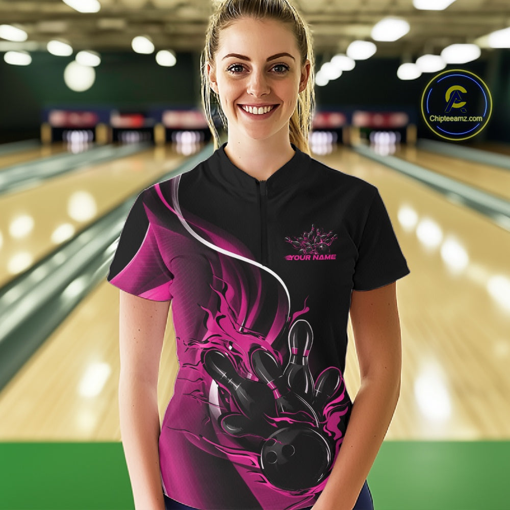 Female model front view at bowling lane wearing black and pink quarter zip shirt with flaming bowling strike artwork and bold energy