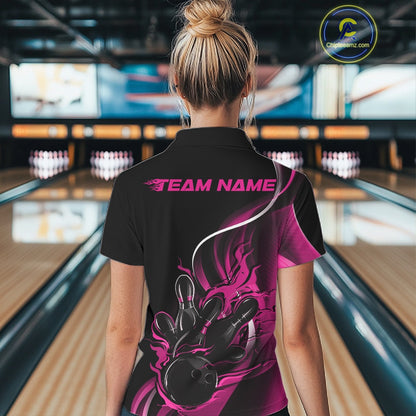 Back view female model in bowling venue wearing black and pink quarter zip shirt featuring flame bowling ball knocking down pins graphics