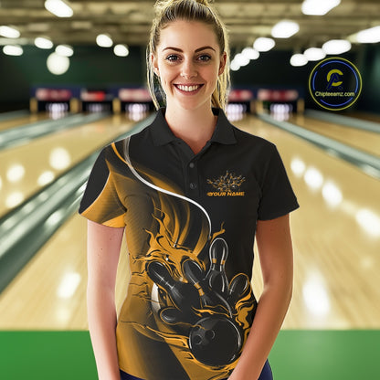 Female model front view in bowling lane wearing black and yellow polo shirt with flaming bowling ball hitting pins in energetic action design.