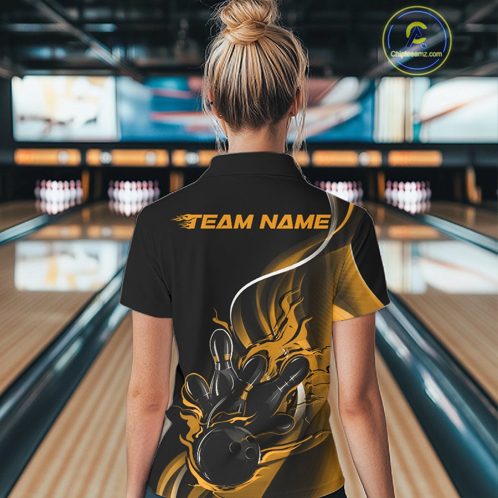 Back view female model inside bowling center wearing black and yellow quarter zip shirt with flame bowling ball and pins action graphics