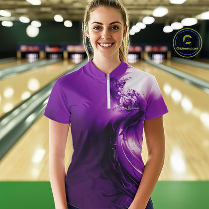Woman wearing a purple bowling shirt with a butterfly design in a bowling alley.