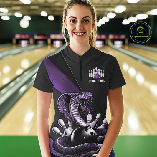 Female model wearing a black bowling quarter-zip in a bowling lane with purple cobra artwork and bowling pin details.