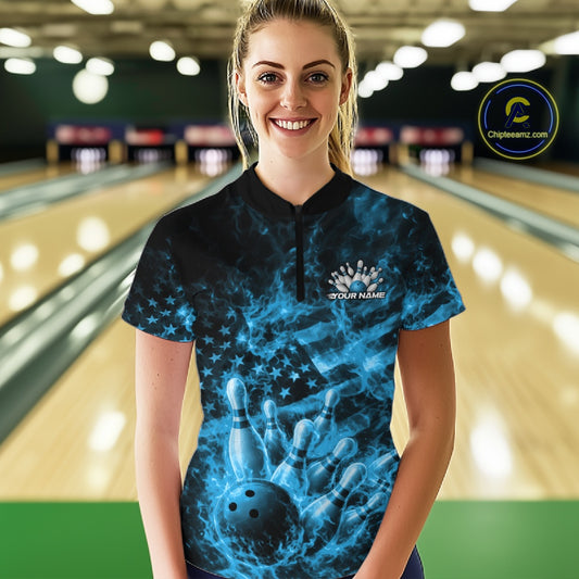 Female model wearing a black and blue bowling quarter-zip in a bowling center with fiery bowling-themed artwork and flag-inspired graphics.
