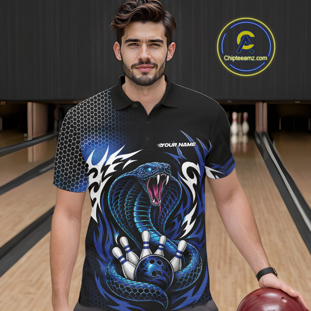 A man wearing a black short-sleeve bowling polo shirt with a blue cobra  snake graphic, standing in a bowling alley holding a bowling ball. 