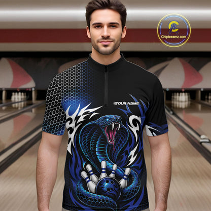 A man wearing a black short-sleeve quarter-zip bowling quarter zip shirt jersey with a blue and black cobra snake graphic, standing in a bowling alley. The jersey features a honeycomb pattern on the right shoulder, a blue cobra snake wrapping around bowling pins on the front, and 'YOUR NAME' printed on the chest.