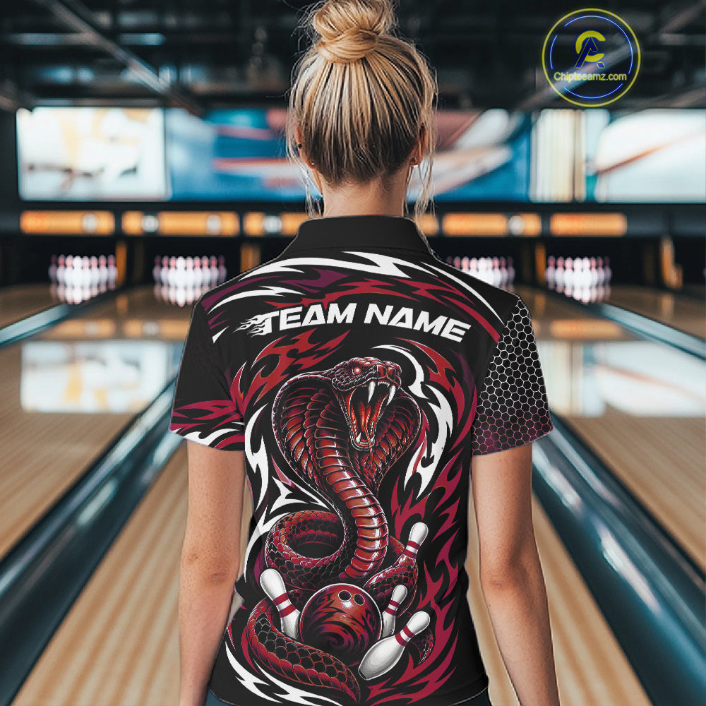 A woman viewed from behind wearing a black short-sleeve bowling polo shirt with a large red and white cobra snake graphic and the text 'TEAM NAME' across the upper back, standing in a bowling alley.