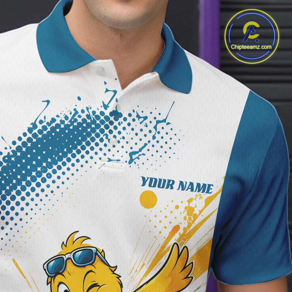 A close-up of a person wearing a custom short-sleeve polo shirt. The shirt has a white body, a teal blue collar and sleeves, and a graphic print featuring a yellow cartoon bird wearing blue sunglasses, blue halftone dots, yellow paint splatters, and the text 'YOUR NAME'.