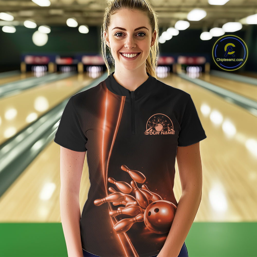 Front view of a female model in a bowling lane wearing a black quarter-zip shirt with orange bowling ball and pins design and clean sporty visuals.