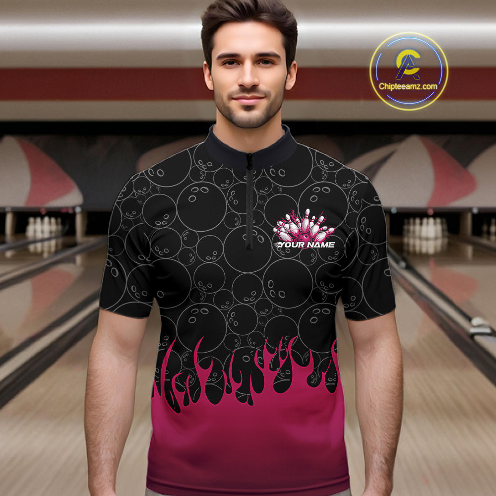 Male model in a bowling alley wearing a black quarter zip shirt, front view featuring bowling ball pattern with vibrant pink flames rising from the bottom and flaming bowling-themed graphics
