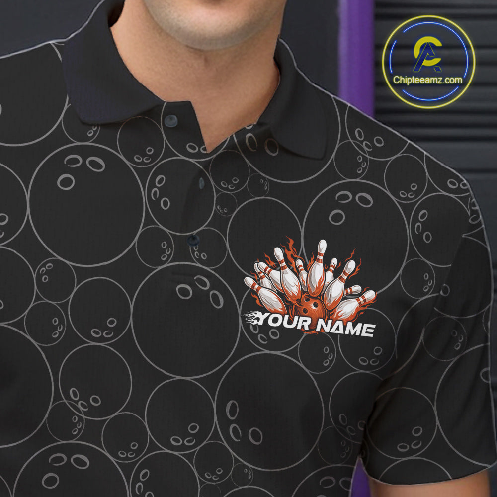 Close-up view of the left chest of a black bowling polo shirt showing bowling ball pattern with vibrant orange flames rising and detailed sporty graphics.