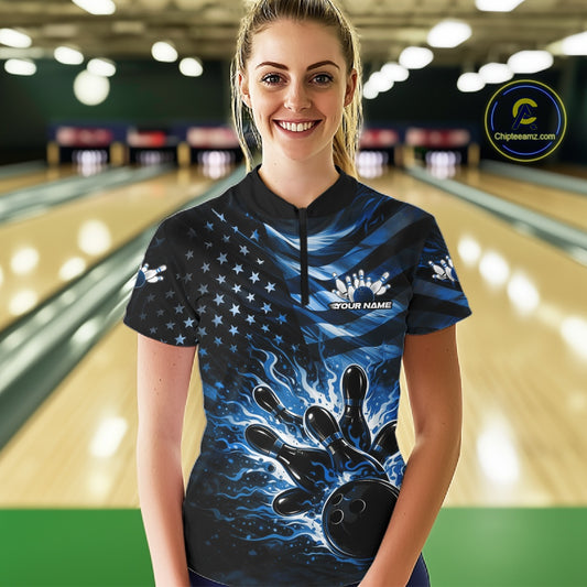 Female model wearing a black bowling quarter-zip shirt at the lane with blue flame bowling strike artwork and patriotic flag details.