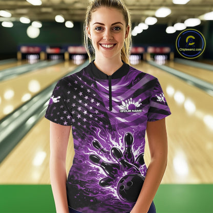Female model wearing a black bowling quarter-zip shirt at the lane featuring purple flame bowling artwork and flag-inspired details.