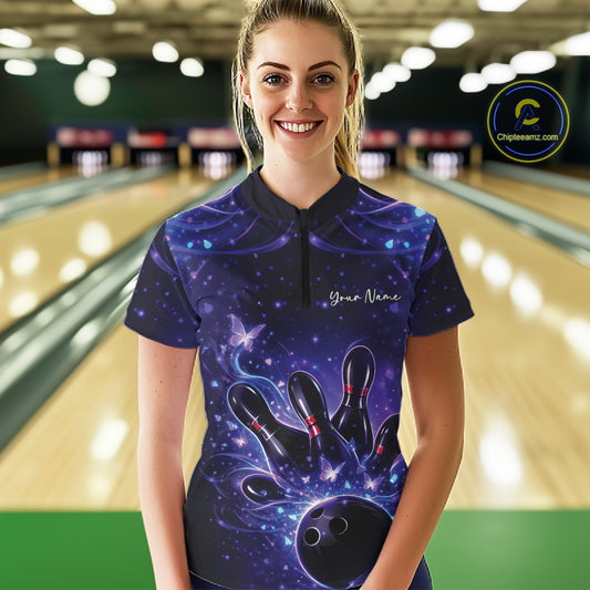 Female model at the bowling lane wearing a blue and purple quarter-zip shirt with glowing butterfly graphics and bowling motifs.