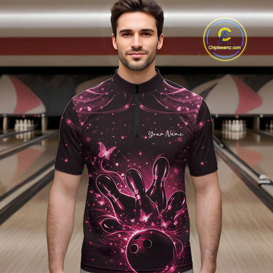 Male model in a black and pink bowling quarter-zip shirt at the lane with butterfly-accented bowling graphics.