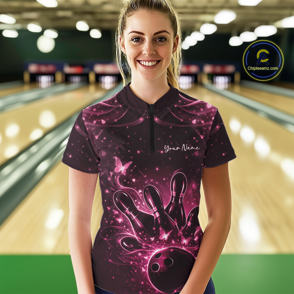Female model in a black and pink bowling quarter-zip shirt wearing bowling-themed artwork with glowing butterflies at the lane.