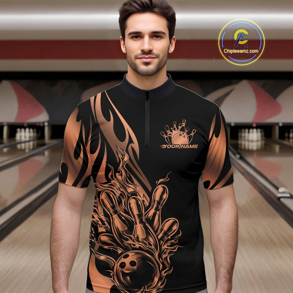 Male model seen front view in a bowling lane wearing a black quarter zip shirt featuring rose gold gradient tribal flame with bowling ball striking pins design.