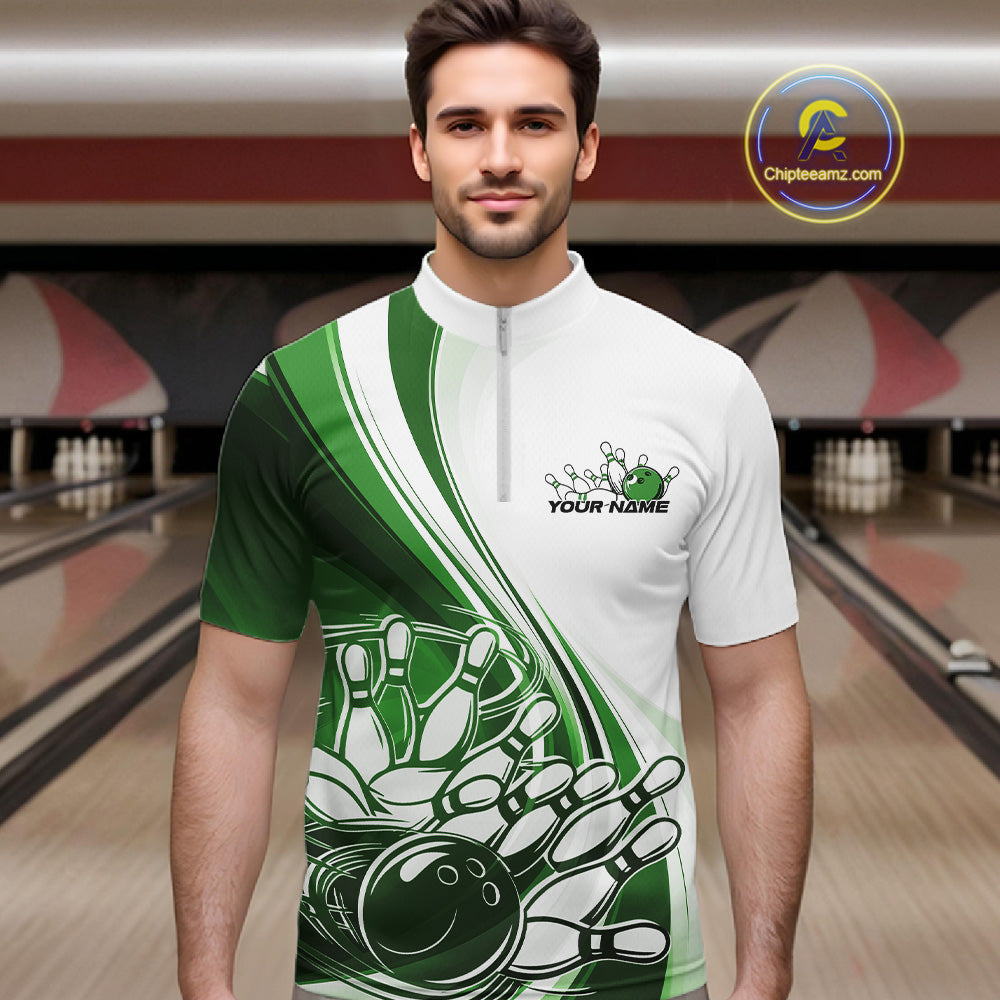 Male model in a bowling alley wearing a white and green quarter zip shirt with a dynamic curved graphic of a bowling ball hitting pins.