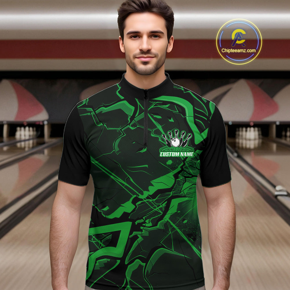 Male model wearing a black and green quarter-zip in a bowling lane with sharp cracked geometric artwork.